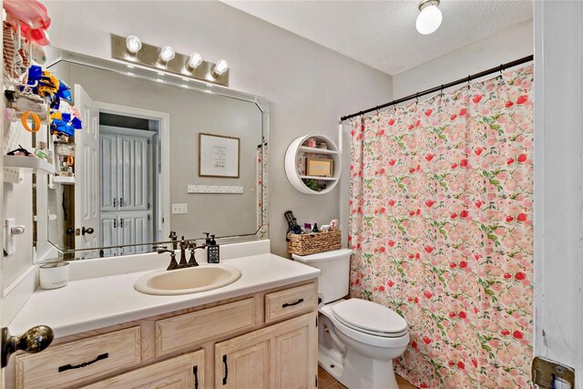 full bath featuring vanity, a textured ceiling, a shower with shower curtain, and toilet