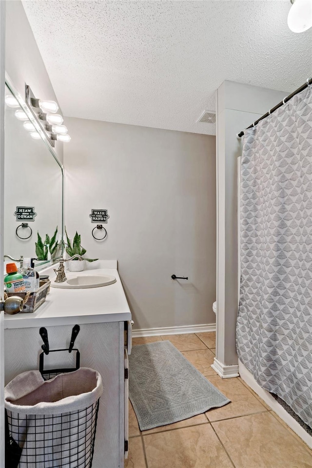 full bathroom with tile patterned flooring, a textured ceiling, visible vents, and double vanity