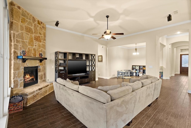 living room featuring a ceiling fan, dark wood-style flooring, crown molding, and a fireplace