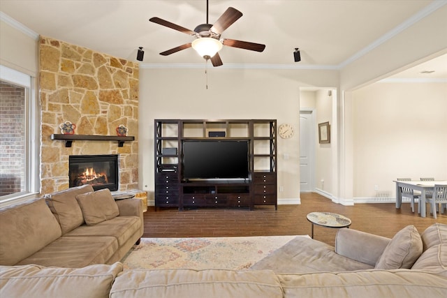 living area with wood finished floors, a ceiling fan, crown molding, baseboards, and a fireplace