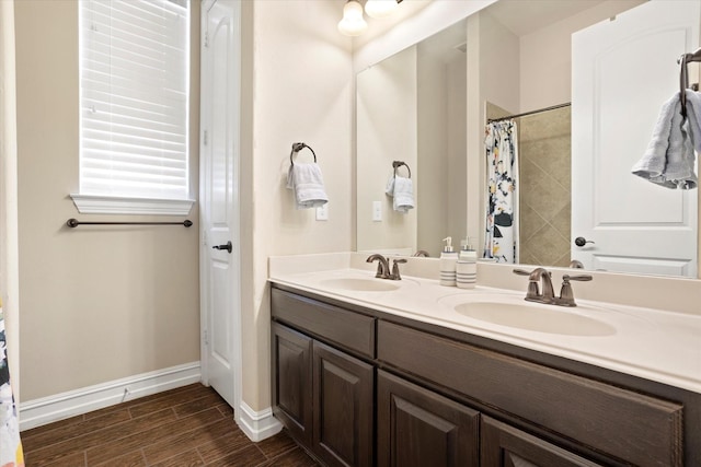 bathroom with double vanity, wood finished floors, baseboards, and a sink