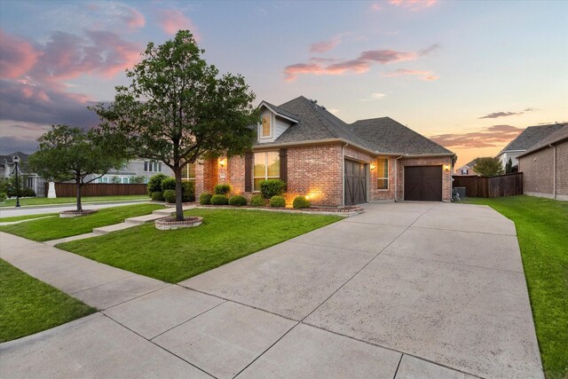 view of front of home with concrete driveway, an attached garage, fence, a yard, and brick siding