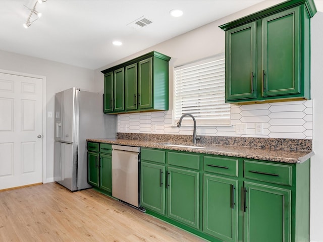 kitchen with a sink, decorative backsplash, light wood-style floors, stainless steel appliances, and visible vents