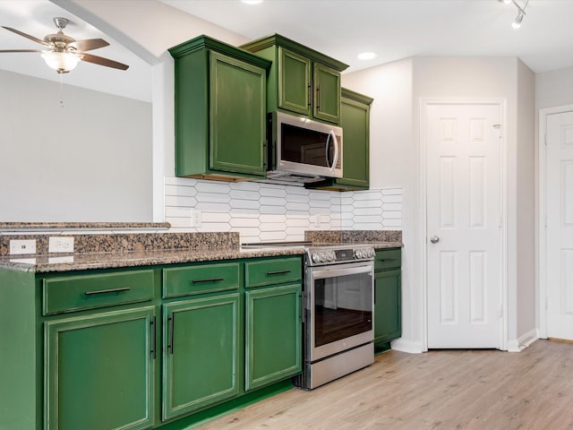 kitchen featuring stainless steel appliances, light wood-type flooring, decorative backsplash, a ceiling fan, and green cabinets