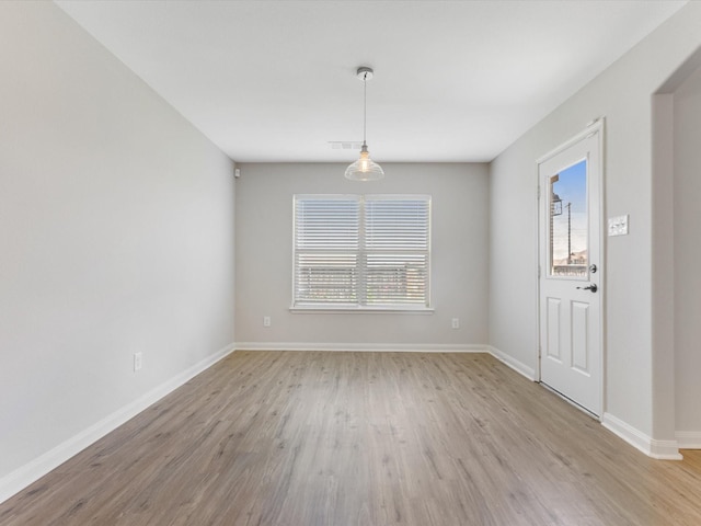 unfurnished dining area with visible vents, light wood finished floors, and baseboards