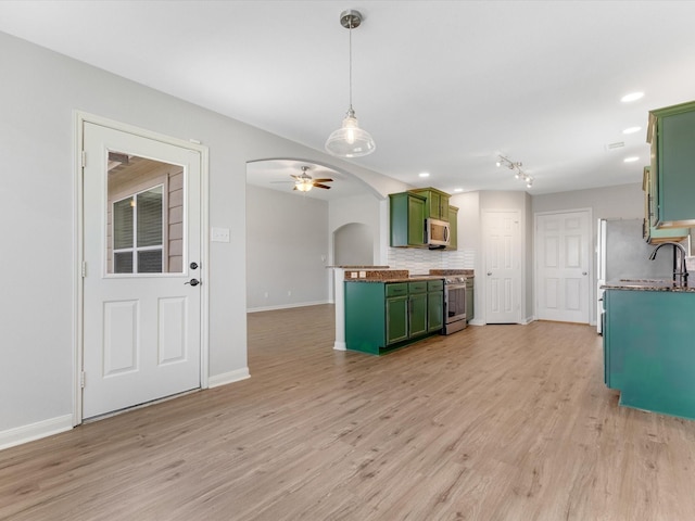 kitchen featuring green cabinetry, arched walkways, baseboards, tasteful backsplash, and appliances with stainless steel finishes