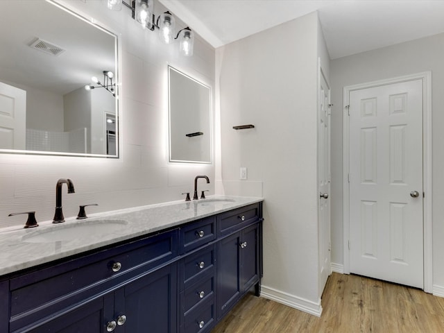 full bath featuring double vanity, wood finished floors, visible vents, and a sink