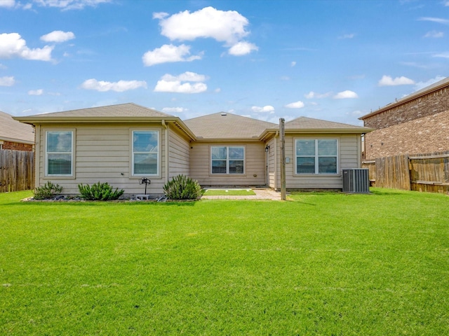 rear view of property featuring a yard, a fenced backyard, and central AC unit