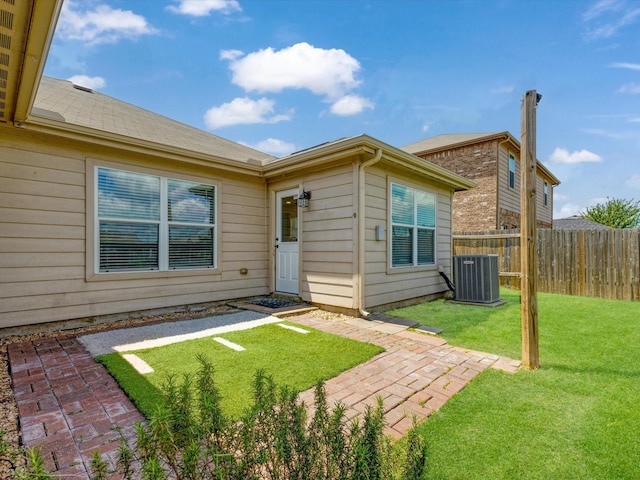 rear view of house with a yard, a patio area, central AC, and fence