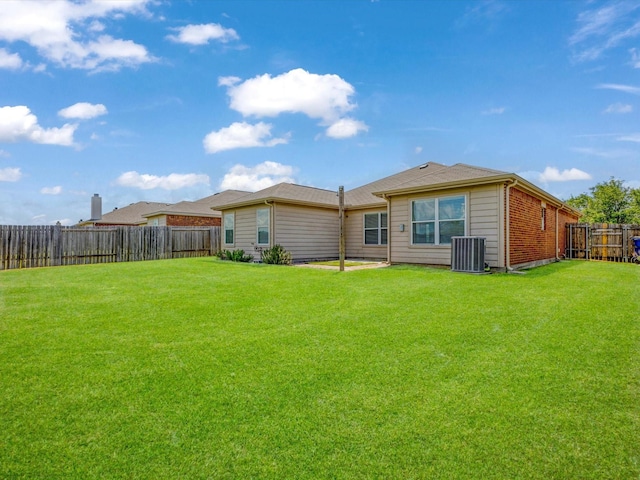rear view of property featuring a fenced backyard, central air condition unit, and a lawn