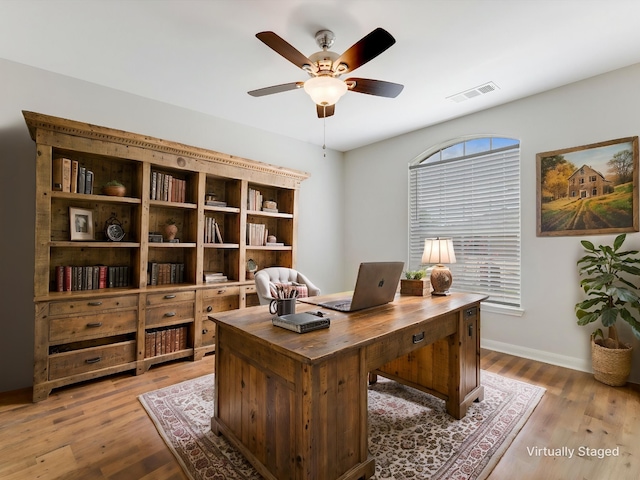 office with light wood-style flooring, visible vents, baseboards, and ceiling fan