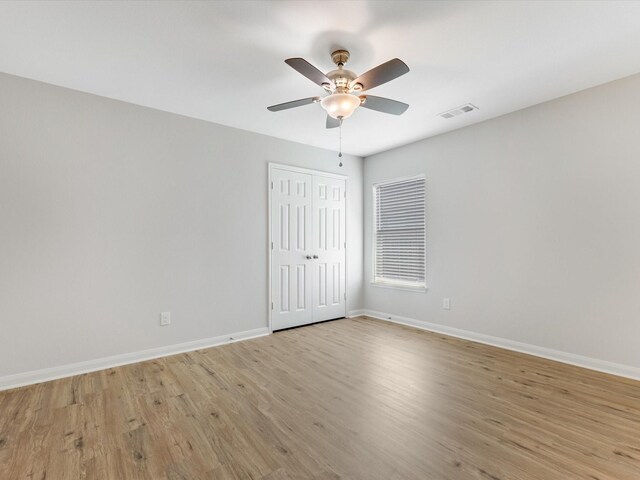 unfurnished room featuring light wood-type flooring, baseboards, a ceiling fan, and visible vents