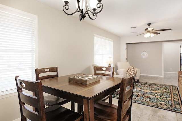 dining space featuring baseboards and ceiling fan with notable chandelier