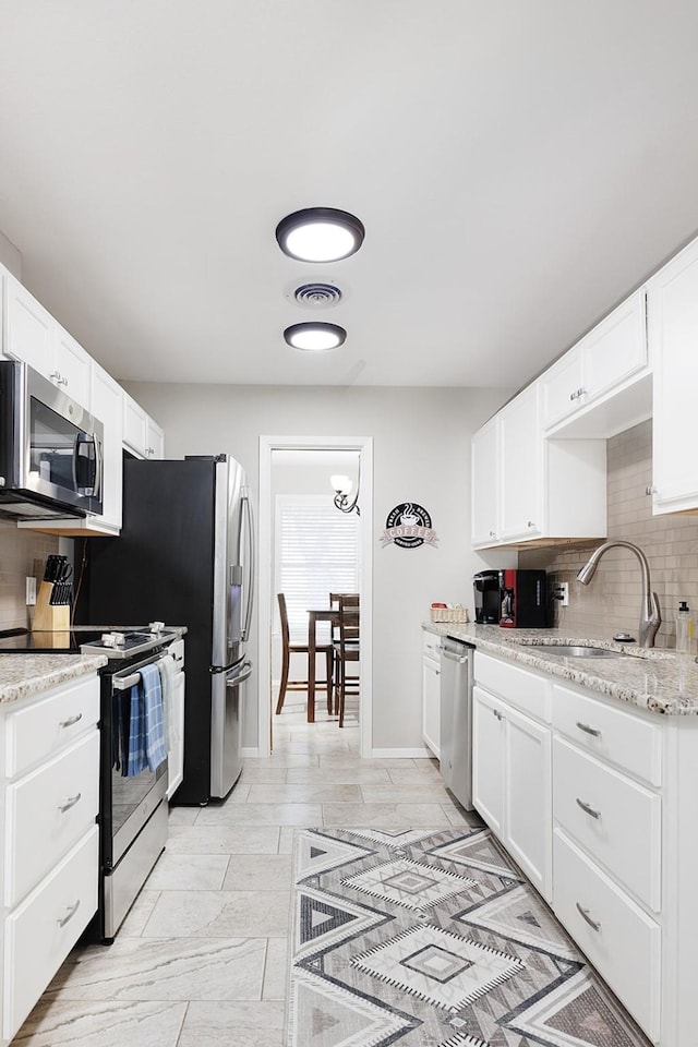 kitchen with white cabinets, visible vents, a sink, decorative backsplash, and appliances with stainless steel finishes