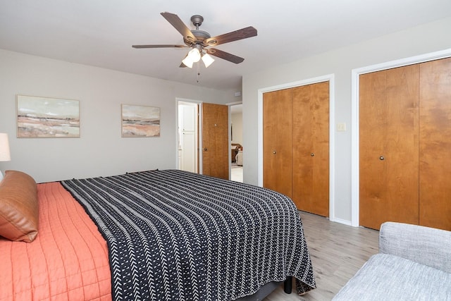bedroom with light wood finished floors, a ceiling fan, and two closets