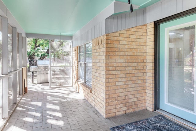 unfurnished sunroom with brick wall and tile patterned flooring