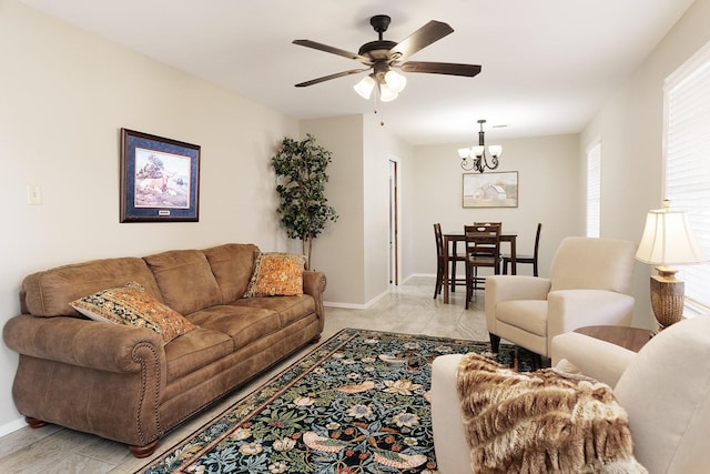 living room with ceiling fan with notable chandelier and baseboards