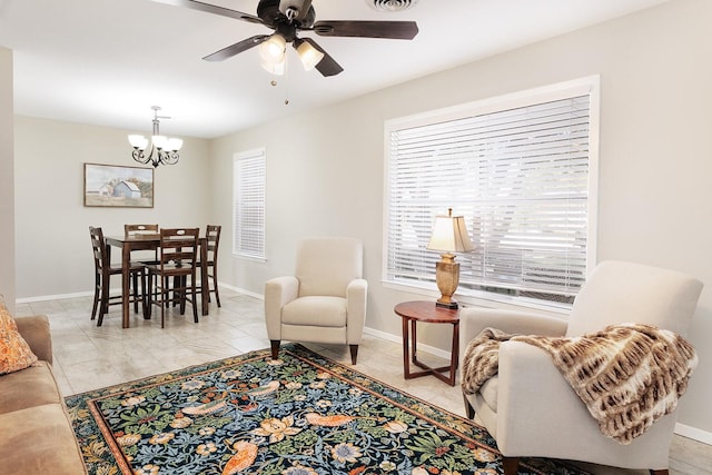 living room with baseboards, a wealth of natural light, and ceiling fan with notable chandelier