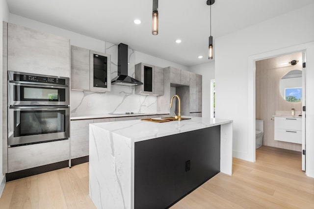 1926 Pueblo St, Dallas, TX 75212 - kitchen with modern cabinets, black electric cooktop, double oven, light wood finished floors, and wall chimney exhaust hood