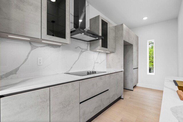 1926 Pueblo St, Dallas, TX 75212 - kitchen featuring black electric stovetop, glass insert cabinets, light wood finished floors, wall chimney exhaust hood, and modern cabinets