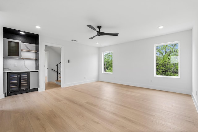 1926 Pueblo St, Dallas, TX 75212 - unfurnished living room with ceiling fan, bar, light wood-style floors, visible vents, and stairway