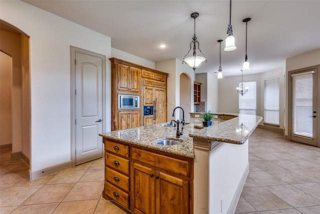 4312 Blue Quail Dr, Mckinney, TX 75072 - kitchen with stainless steel microwave, light tile patterned floors, a sink, light stone countertops, and a center island with sink
