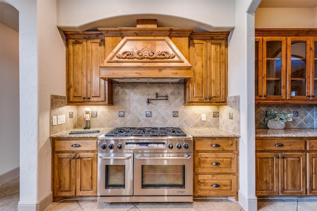 4312 Blue Quail Dr, Mckinney, TX 75072 - kitchen with range with two ovens, light stone counters, brown cabinets, and tasteful backsplash