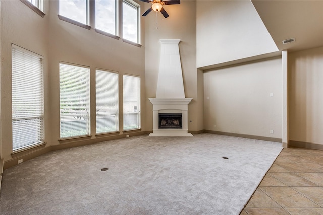 4312 Blue Quail Dr, Mckinney, TX 75072 - unfurnished living room with a ceiling fan, a high ceiling, plenty of natural light, a fireplace with raised hearth, and light tile patterned flooring