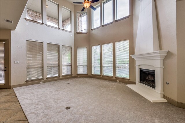 4312 Blue Quail Dr, Mckinney, TX 75072 - unfurnished living room with ceiling fan, a towering ceiling, a fireplace, light carpet, and baseboards