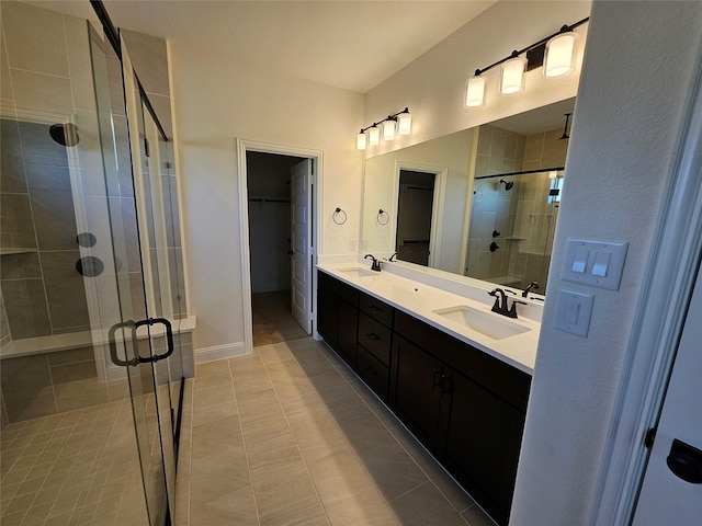 bathroom with a spacious closet, a sink, double vanity, and a stall shower