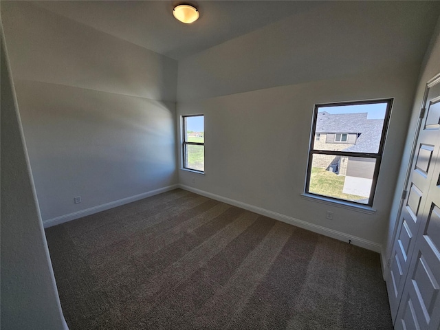 carpeted empty room with vaulted ceiling and baseboards