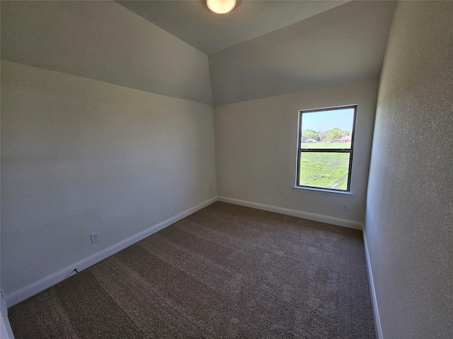 carpeted spare room featuring lofted ceiling and baseboards