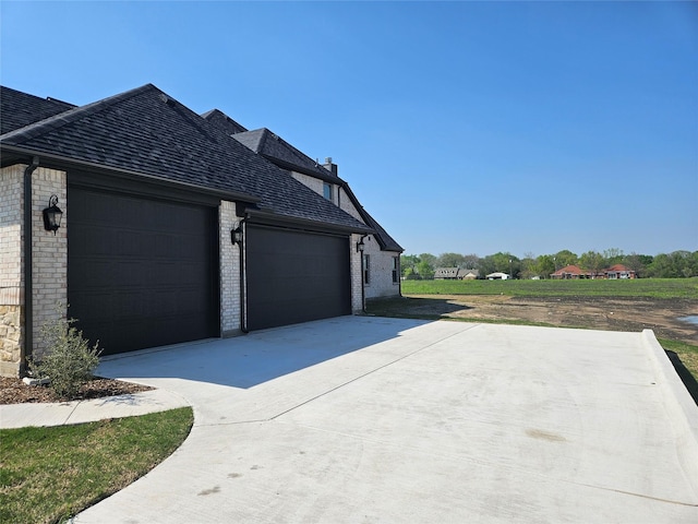 view of side of property featuring driveway, brick siding, and a garage