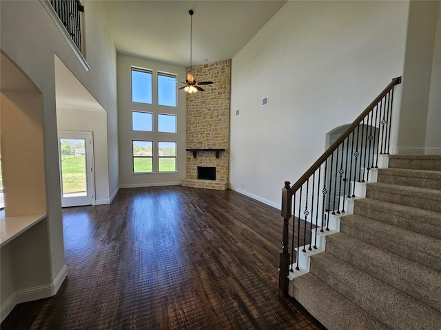 unfurnished living room featuring stairway, plenty of natural light, a towering ceiling, and ceiling fan