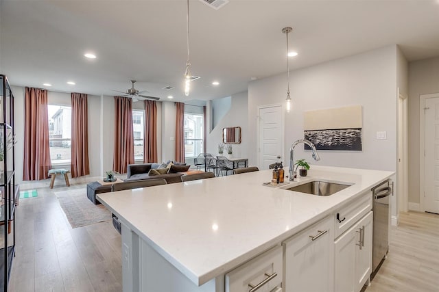 kitchen with plenty of natural light, a center island with sink, white cabinetry, and a sink