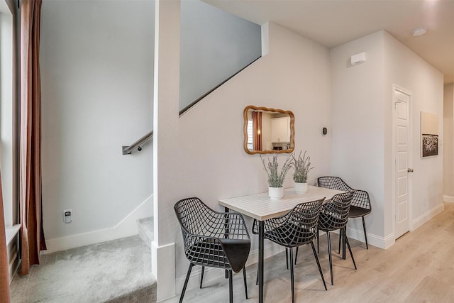dining space with stairway, baseboards, and light wood-style flooring