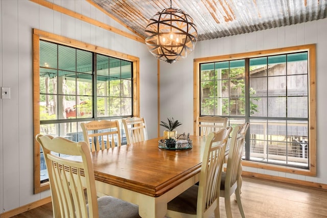 230 W Sesame St, Karnack, TX 75661 - dining room with a chandelier, wood finished floors, wood walls, lofted ceiling, and baseboards