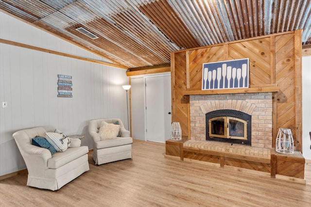 230 W Sesame St, Karnack, TX 75661 - living area featuring wood finished floors, a brick fireplace, lofted ceiling, and wooden walls