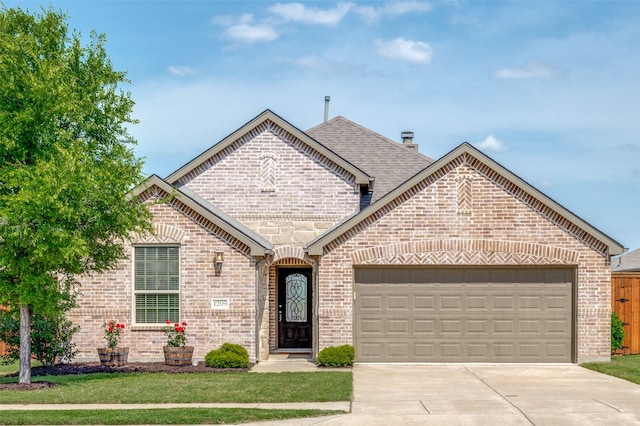 1209 Roadrunner Dr, Little Elm, TX 75068 - french country style house with brick siding, a garage, concrete driveway, and a chimney