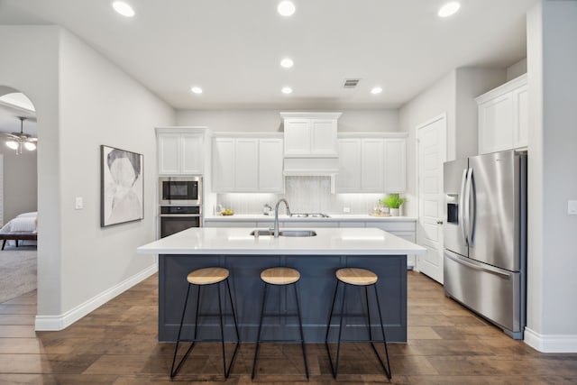 8517 Holliday Creek Way, Mckinney, TX 75071 - kitchen featuring stainless steel appliances, a sink, a center island with sink, dark wood-style floors, and white cabinetry