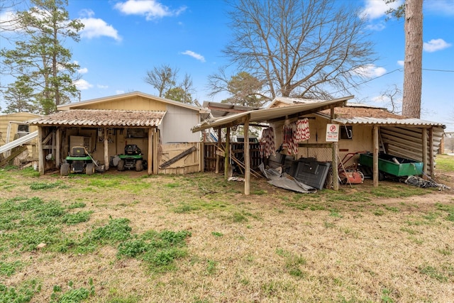 rear view of house featuring an outdoor structure, an outbuilding, and a lawn