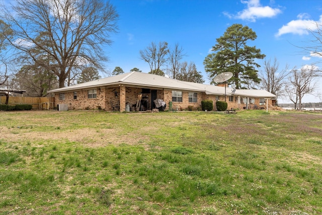 back of house with brick siding, a lawn, and fence