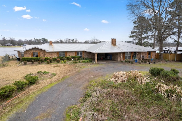 view of front of property with an attached carport, a chimney, aphalt driveway, and fence