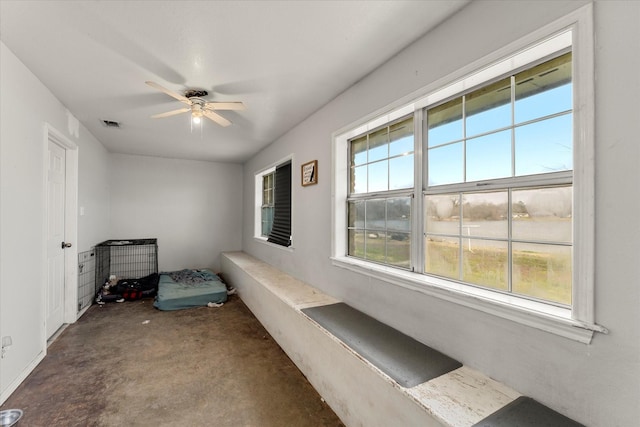 interior space featuring concrete floors, a ceiling fan, and visible vents