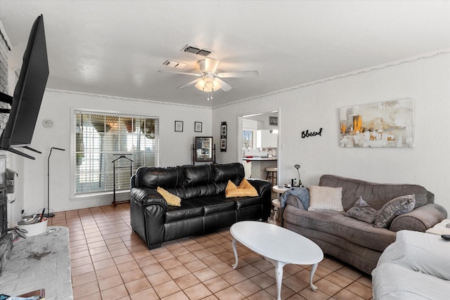 living area featuring ornamental molding, a ceiling fan, visible vents, and light tile patterned floors