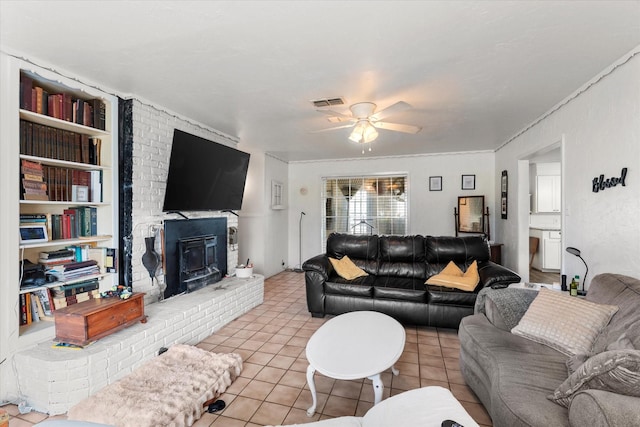 living room with tile patterned flooring, visible vents, ornamental molding, built in features, and ceiling fan