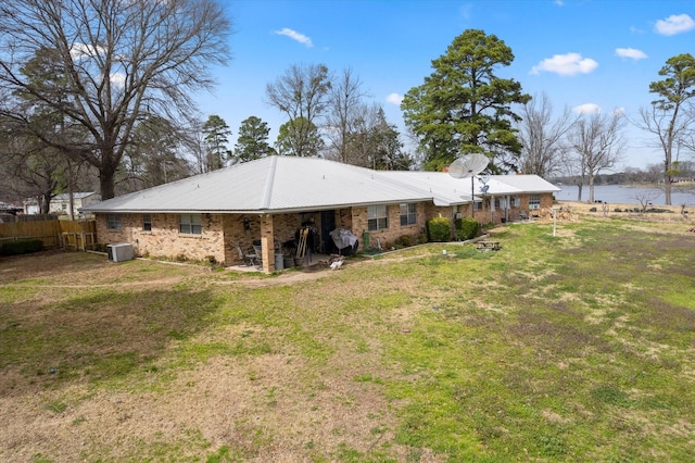 rear view of house with a lawn, a water view, fence, cooling unit, and brick siding