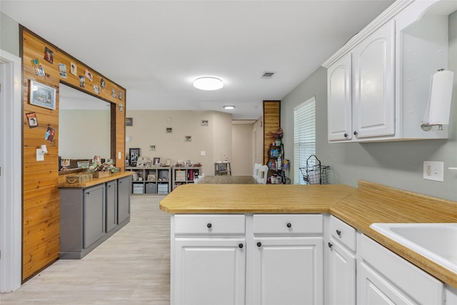 103 Elm St, Roxton, TX 75477 - kitchen with light wood-type flooring, light countertops, white cabinets, a peninsula, and visible vents