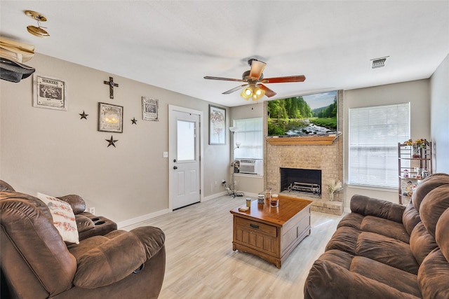 103 Elm St, Roxton, TX 75477 - living room with visible vents, a ceiling fan, a brick fireplace, and light wood-style floors