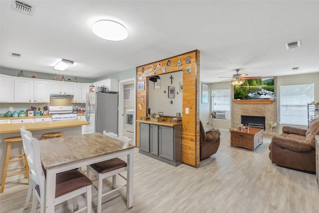 103 Elm St, Roxton, TX 75477 - kitchen with under cabinet range hood, white gas range, visible vents, freestanding refrigerator, and open floor plan